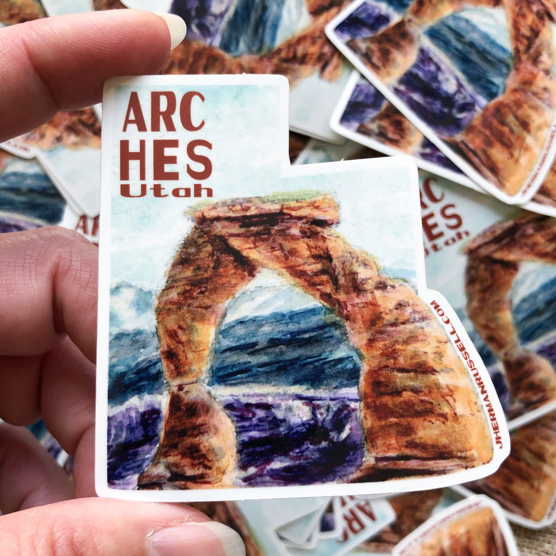 Closeup of hand holding Arches National Park sticker for scale. Jhermanrussell.com