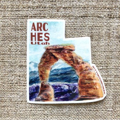 Arches National Park, Utah collectible vinyl sticker. Featuring the Delicate Arch in watercolor with red text that reads Arches Utah. Jhermanrussell.com